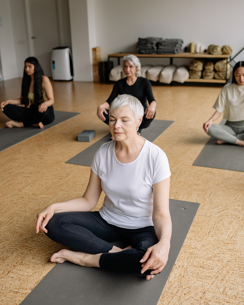 Elderly Woman in White Shirt Sitting on Yoga Mat